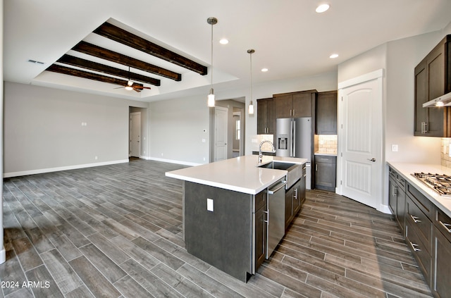 kitchen with dark brown cabinetry, a center island with sink, ceiling fan, hanging light fixtures, and beam ceiling