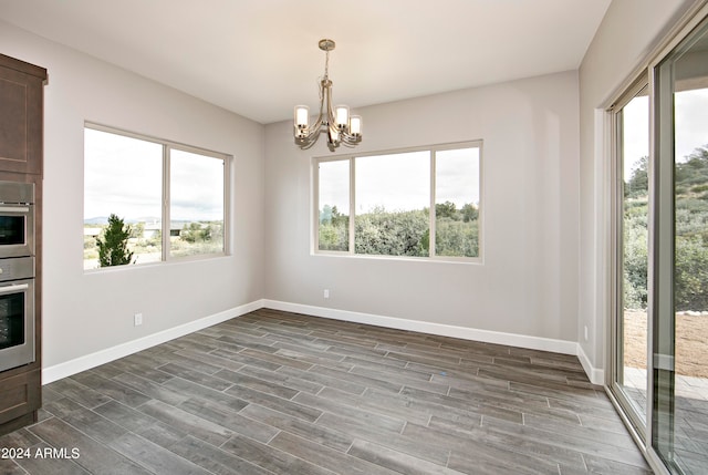 unfurnished dining area with an inviting chandelier and dark wood-type flooring