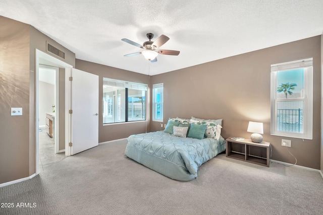 bedroom featuring ceiling fan, light carpet, and a textured ceiling