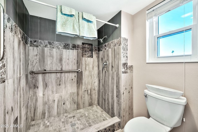 bathroom featuring toilet and a tile shower