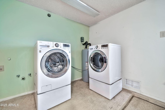 washroom featuring a textured ceiling, water heater, and washing machine and clothes dryer