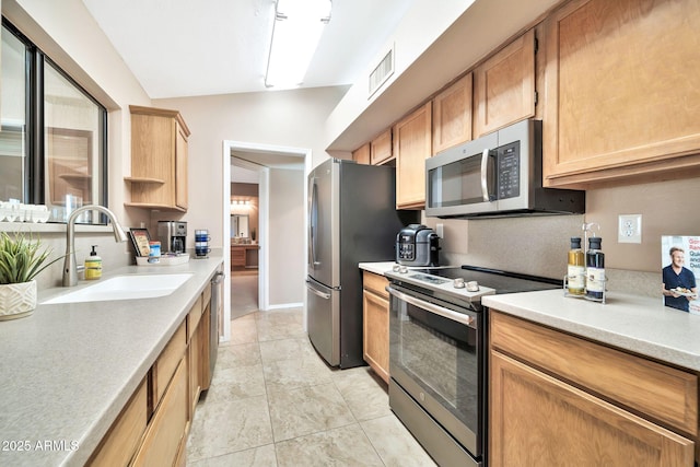 kitchen with vaulted ceiling, sink, stainless steel appliances, and light tile patterned flooring