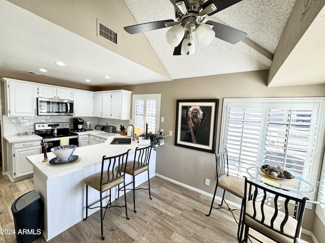 kitchen with white cabinets, appliances with stainless steel finishes, and light wood-type flooring