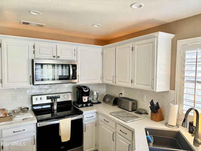 kitchen with appliances with stainless steel finishes, sink, and white cabinets