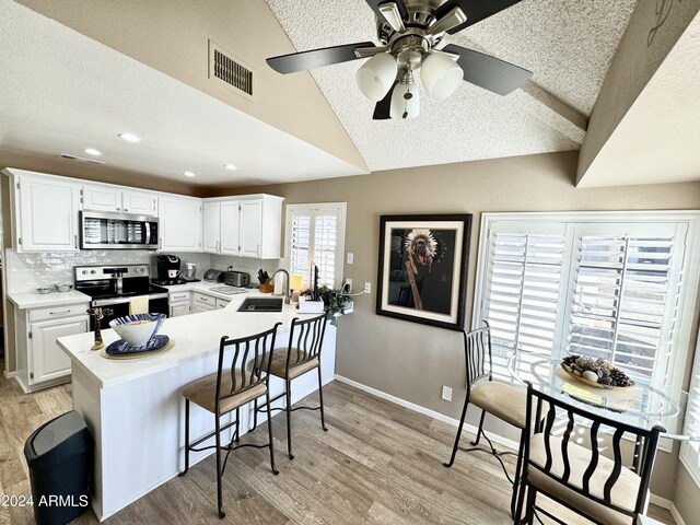 kitchen with stainless steel appliances, white cabinets, and light hardwood / wood-style flooring