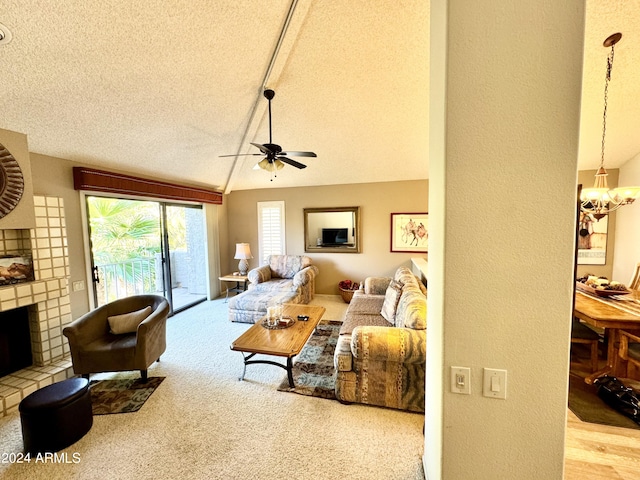 carpeted living room featuring a brick fireplace, ceiling fan with notable chandelier, a textured ceiling, and vaulted ceiling