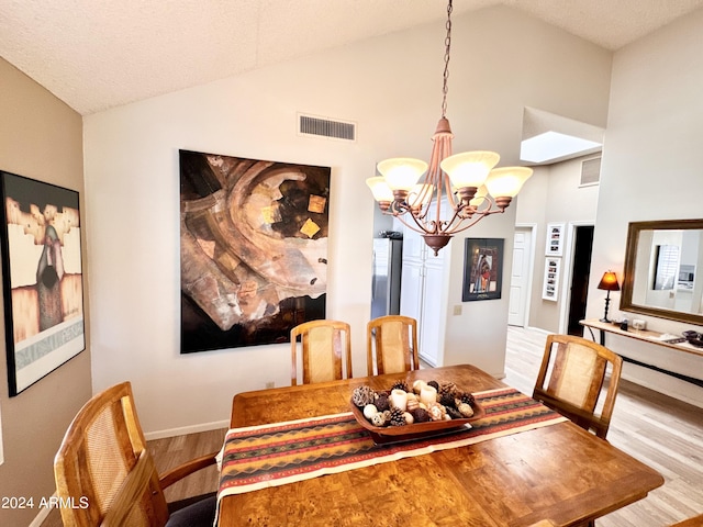 dining room with a notable chandelier, high vaulted ceiling, and light hardwood / wood-style floors