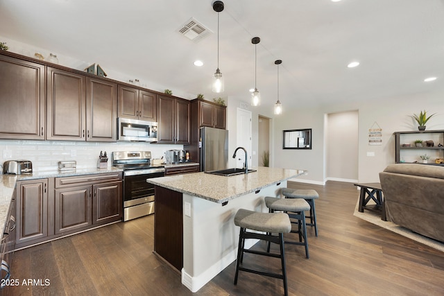 kitchen with a breakfast bar, dark wood-style floors, stainless steel appliances, and a sink