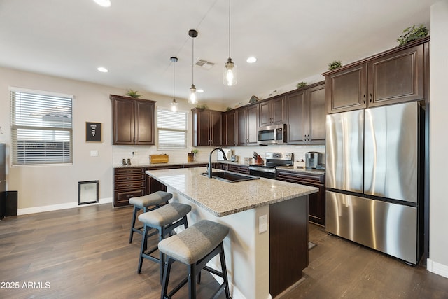 kitchen featuring dark brown cabinets, a sink, appliances with stainless steel finishes, dark wood-style flooring, and visible vents
