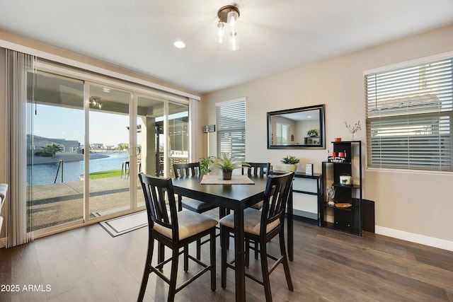 dining area featuring recessed lighting, wood finished floors, a water view, and baseboards