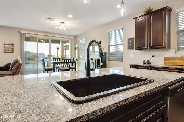 kitchen featuring dark brown cabinetry, stainless steel dishwasher, a sink, and a healthy amount of sunlight