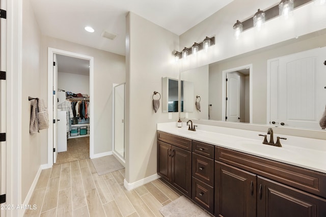 full bathroom featuring wood finished floors, a sink, a shower stall, and double vanity