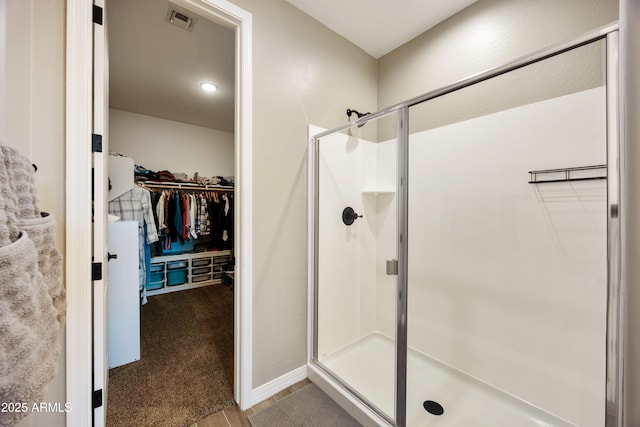 full bathroom with a shower stall, a walk in closet, and visible vents