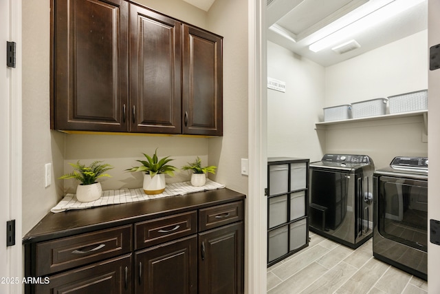 clothes washing area featuring cabinet space, washing machine and dryer, and light wood finished floors