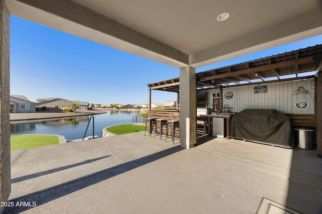 view of patio / terrace with grilling area, outdoor dry bar, a water view, and a residential view