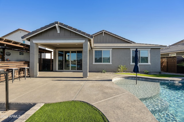 rear view of property featuring outdoor dry bar, fence, stucco siding, board and batten siding, and a patio area