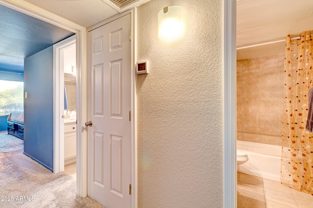 hall with a textured ceiling and light colored carpet