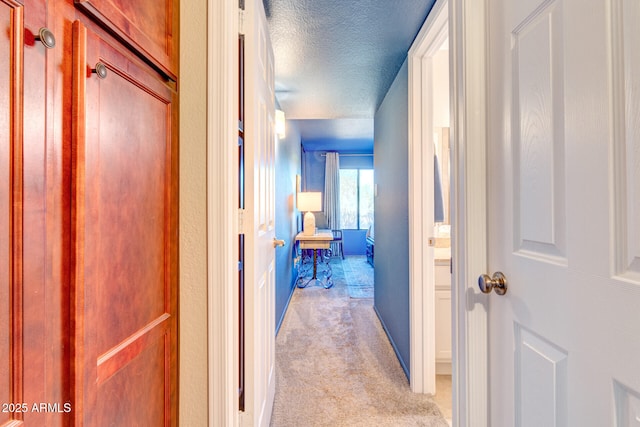 hall featuring a textured ceiling and light carpet