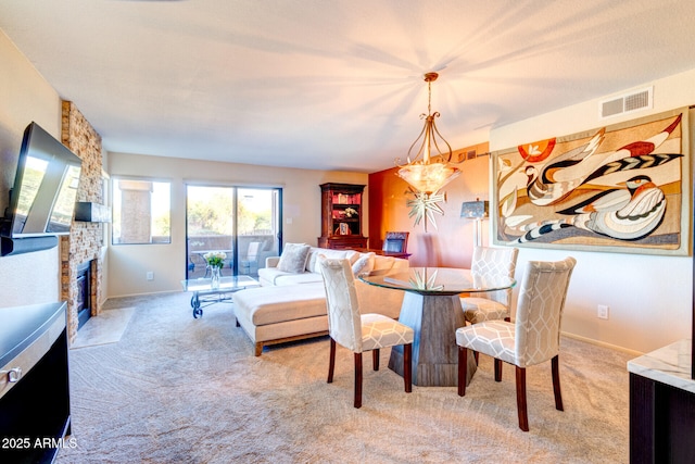 dining room featuring light carpet and a stone fireplace