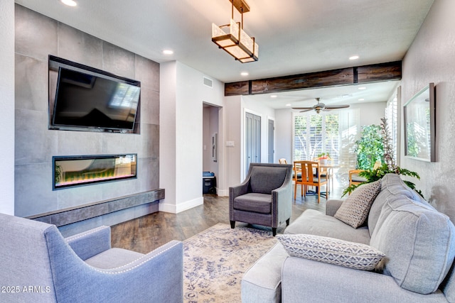 living room with wood-type flooring, a fireplace, ceiling fan, and beam ceiling