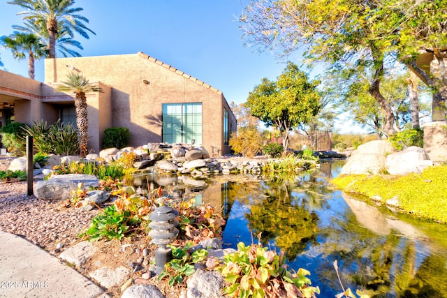 view of side of home featuring a small pond