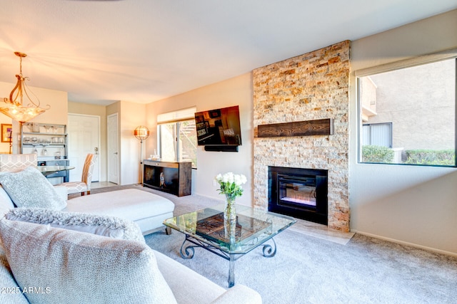 living room featuring an inviting chandelier, carpet flooring, and a stone fireplace