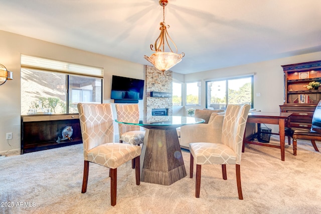 dining area featuring light colored carpet and a fireplace