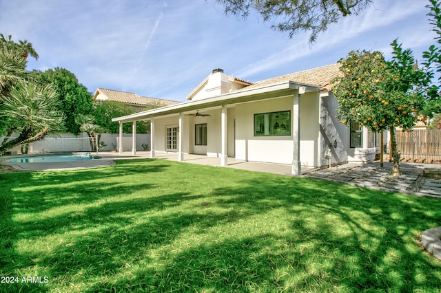 back of property featuring ceiling fan, a patio area, a fenced in pool, and a yard