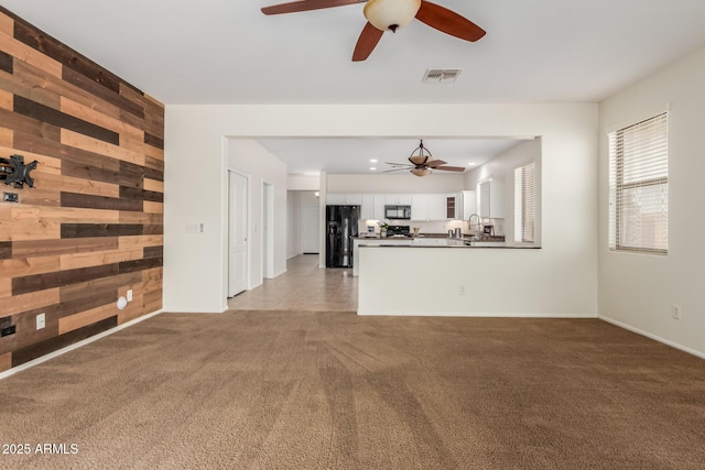 871 E Melanie St, San Tan Valley, AZ 85140 - unfurnished living room featuring ceiling fan, wood walls, carpet, and a sink