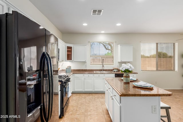 871 E Melanie St, San Tan Valley, AZ 85140 - kitchen featuring black appliances, a sink, light tile patterned floors, a kitchen bar, and a center island