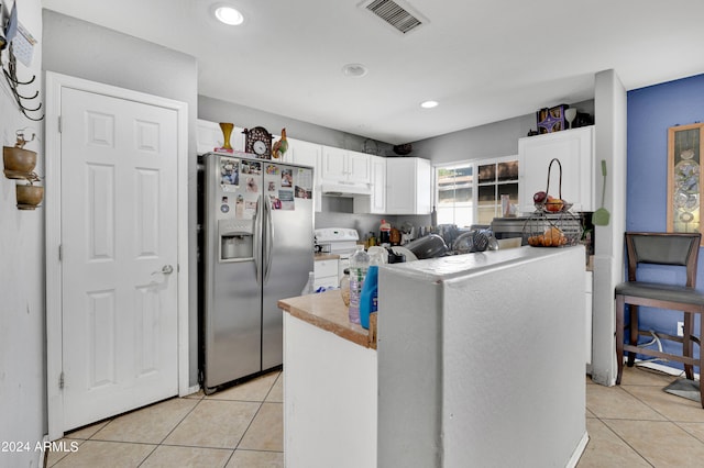 kitchen featuring stainless steel fridge, white cabinetry, light tile patterned flooring, and white stove