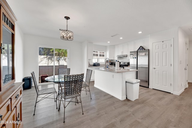 dining space with a chandelier, sink, and light wood-type flooring