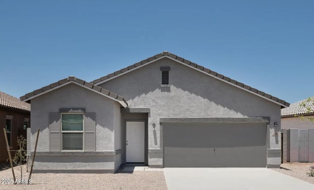 view of front of house featuring concrete driveway, a tile roof, an attached garage, and stucco siding