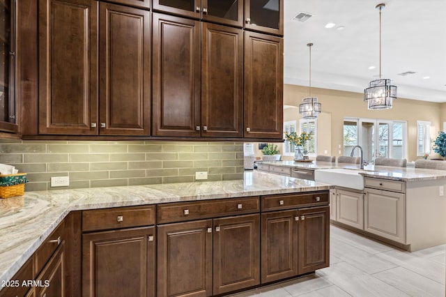 kitchen featuring tasteful backsplash, sink, pendant lighting, and dark brown cabinetry