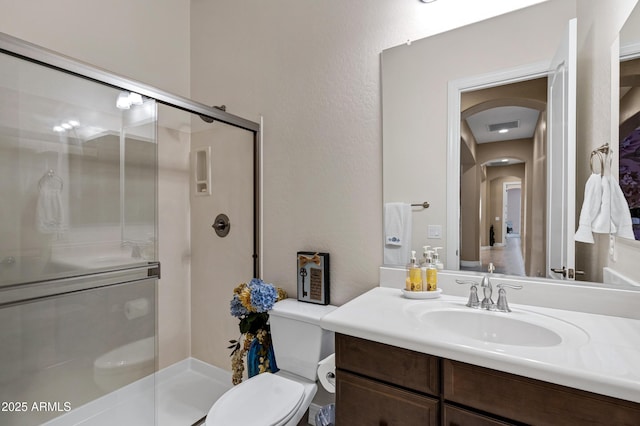 bathroom with vanity, a shower with shower door, and toilet