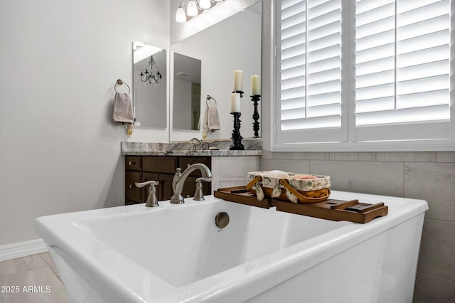 bathroom with a tub to relax in, sink, and tile patterned flooring