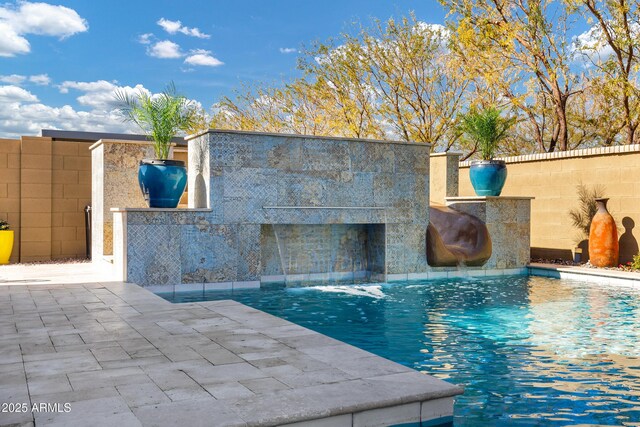 view of swimming pool featuring pool water feature, a water slide, an outdoor bar, and a patio area