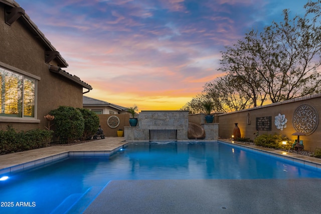 pool at dusk featuring a water slide