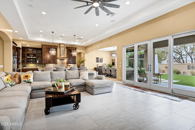 tiled living room featuring ceiling fan, a raised ceiling, and a wealth of natural light