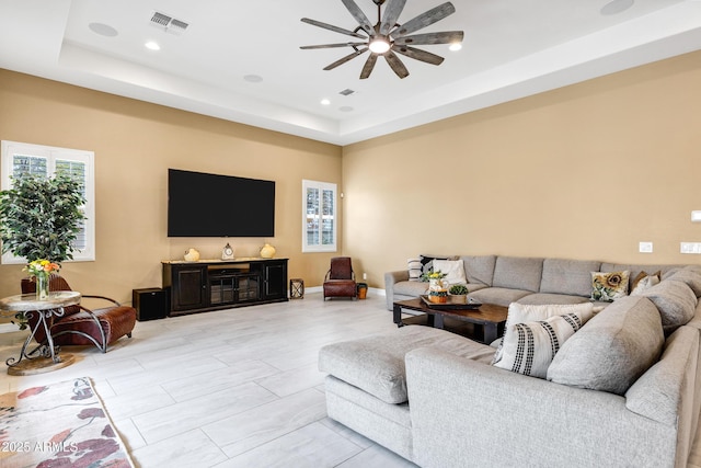 living room featuring ceiling fan and a tray ceiling