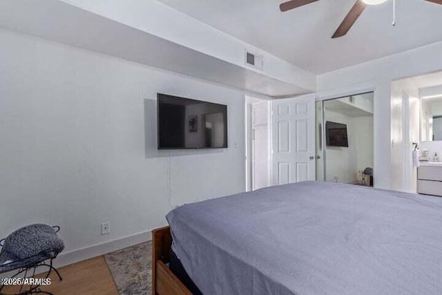 bedroom featuring ceiling fan, visible vents, wood finished floors, baseboards, and ensuite bathroom