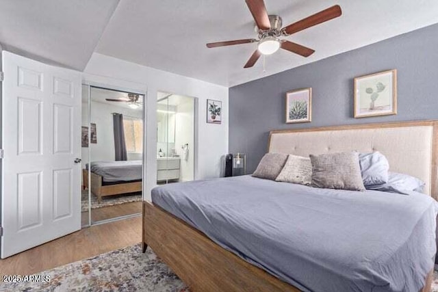 bedroom with ceiling fan, ensuite bath, and wood finished floors