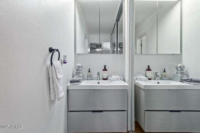 bathroom featuring ceiling fan, a textured wall, and vanity