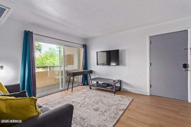 living room featuring baseboards, a textured ceiling, and wood finished floors