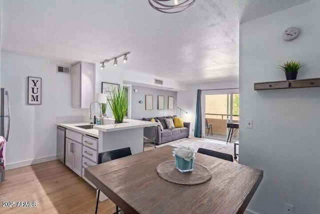 dining space with baseboards, visible vents, and light wood finished floors
