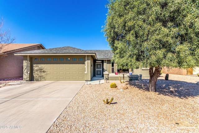 view of front facade featuring driveway, roof with shingles, an attached garage, and stucco siding