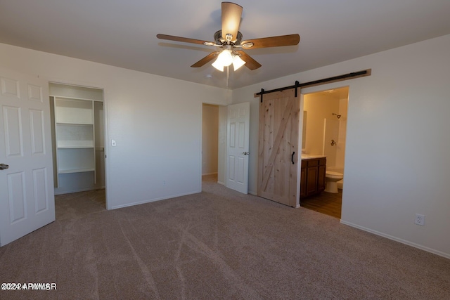 unfurnished bedroom featuring light carpet, a closet, ceiling fan, and a barn door