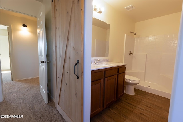 bathroom with wood-type flooring, vanity, a shower, and toilet