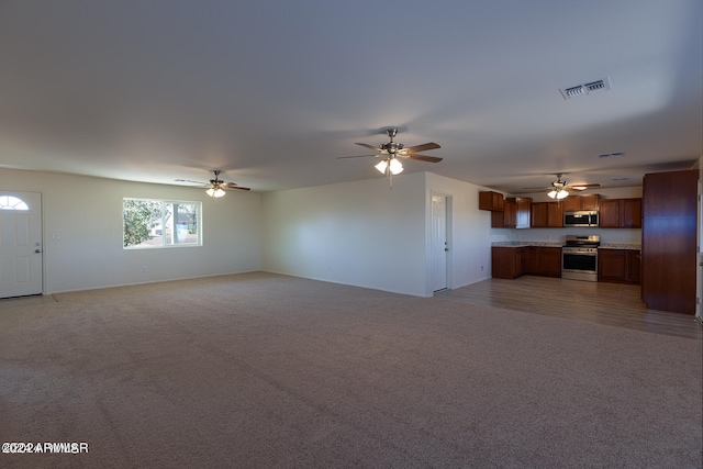 unfurnished living room with ceiling fan and light colored carpet