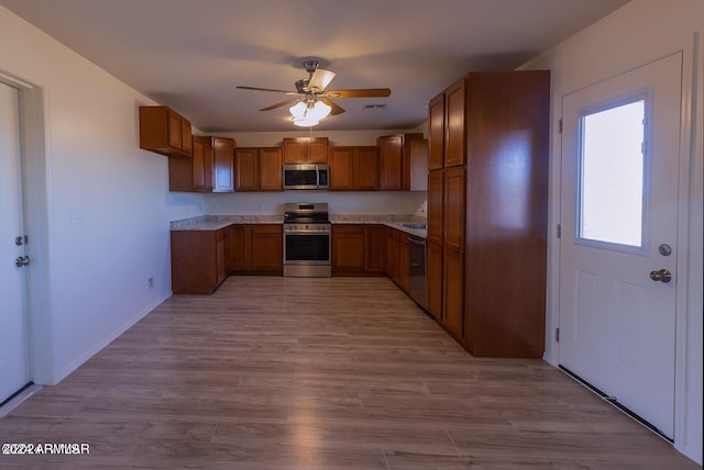 kitchen featuring appliances with stainless steel finishes, light wood-type flooring, sink, and ceiling fan